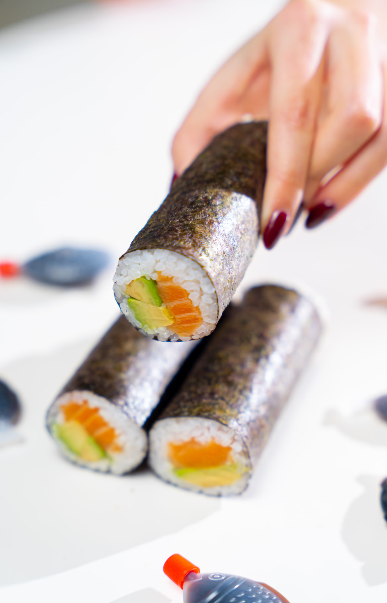 Hand reaching for a salmon avocado MAKU roll